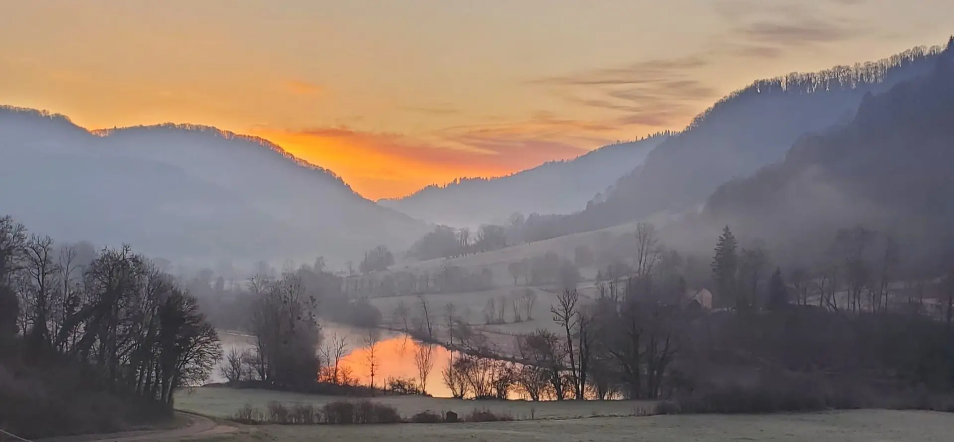 Lever de soleil sur la vallée de Montjoie, le lac embrasé dans la brume du matin